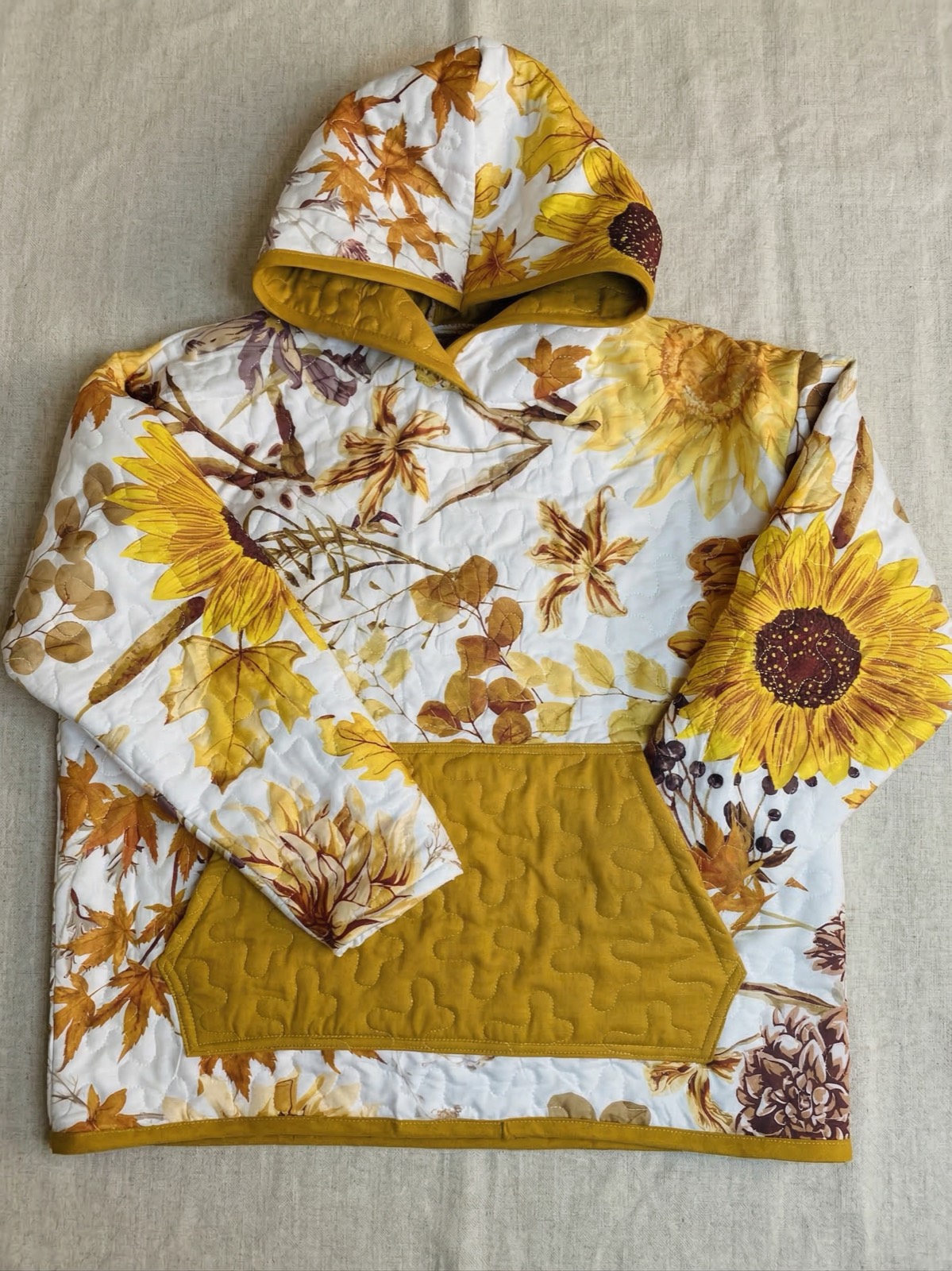 Quilted hoodie with sunflower and autumn leaf pattern on golden yellow backing